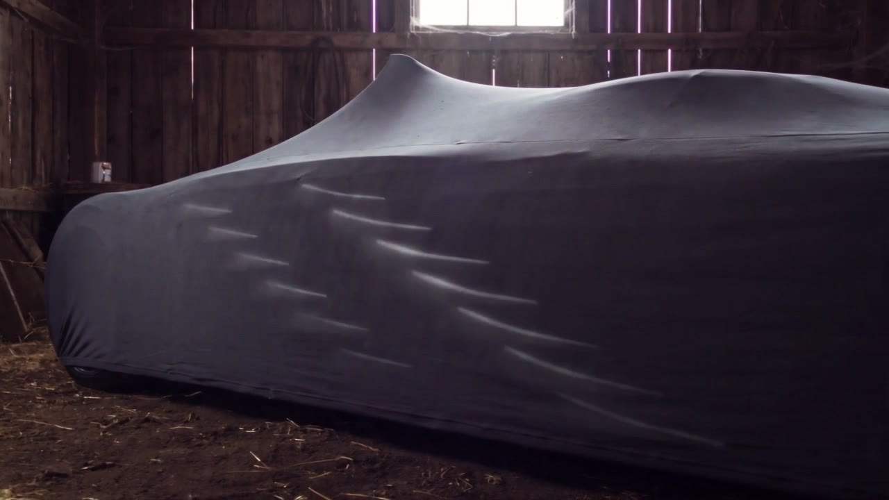 Six slashes of light glowing through a car cover in the dark barn